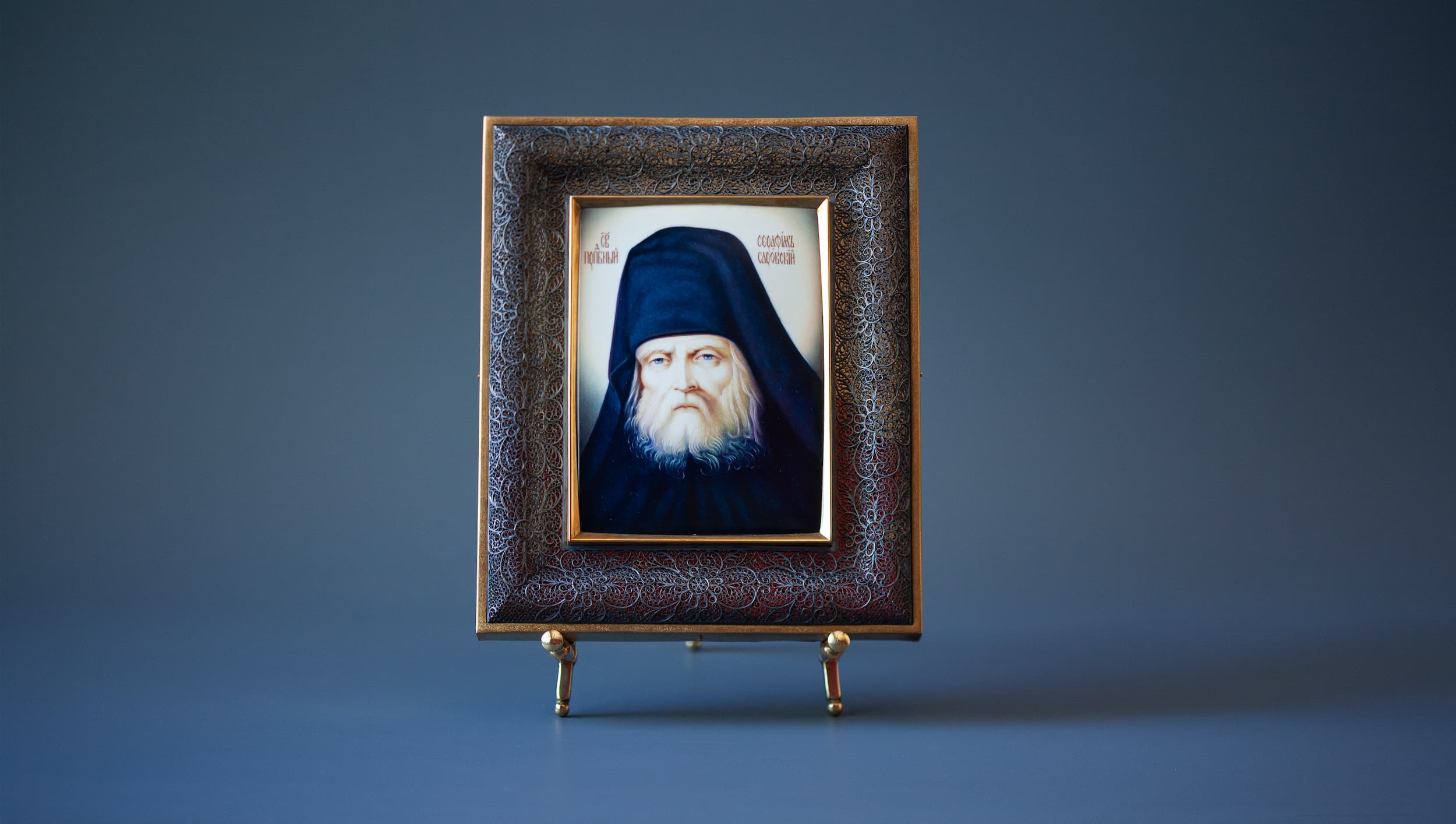 Икона Серафима Саровского на подставке на фотофоне. Фото 1. Рукописная икона Серафим Саровский в серебряном окладе в технике миниатюрной живописи по эмали. Фото 1. Икона целиком на сером фоне
